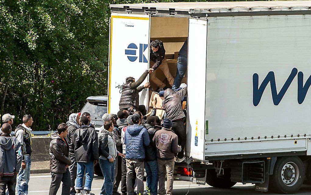 Vluchtelingen klimmen in Calais in een opengebroken vrachtwagen. Beeld AFP