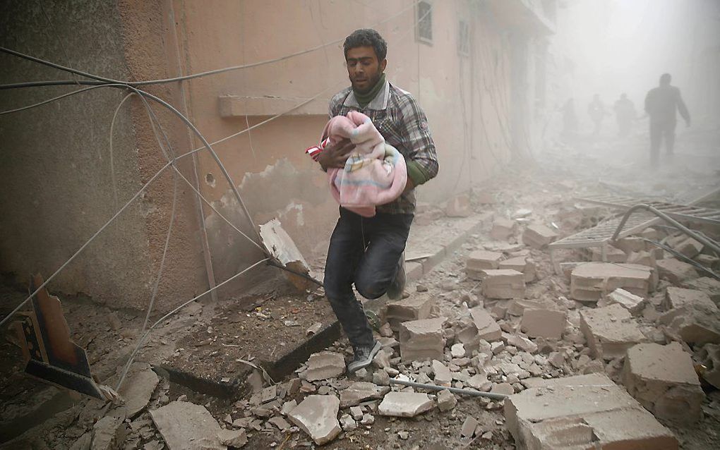 Een man draagt een baby in het Syrische Douma. beeld AFP