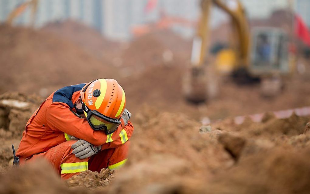 Een Chinese reddingswerker tijdens de zoektocht naar overlevenden na een aardverschuiving in China. Beeld EPA