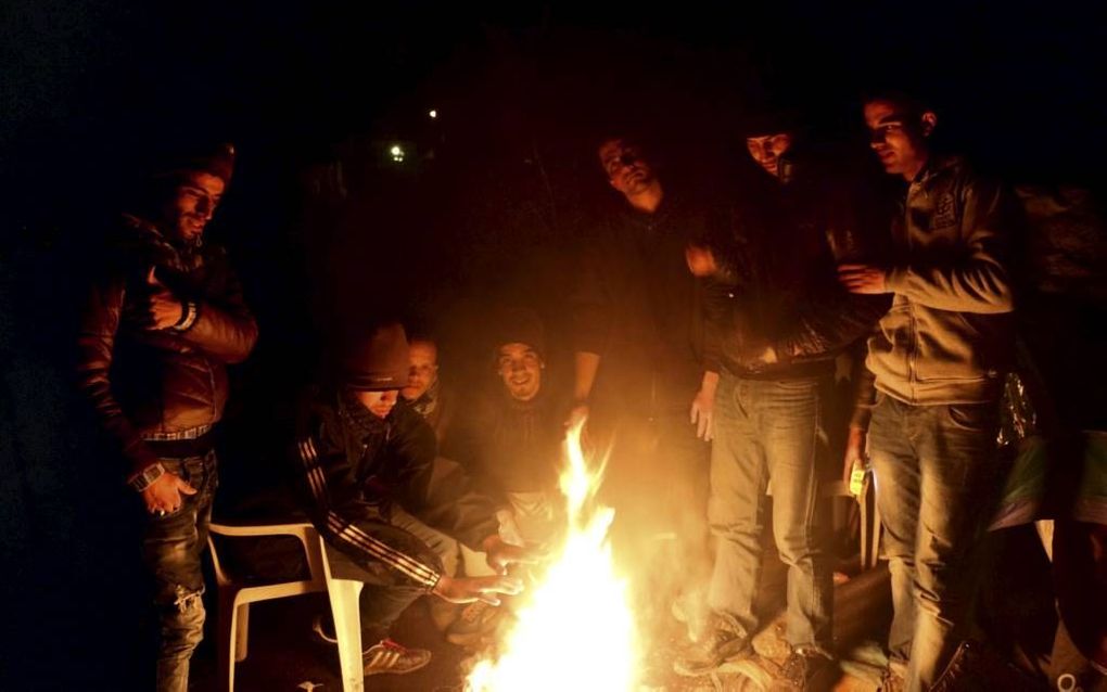 Marokkaanse jongeren warmen zich rond een vuurtje op Lesbos. Beeld Jilke Tanis