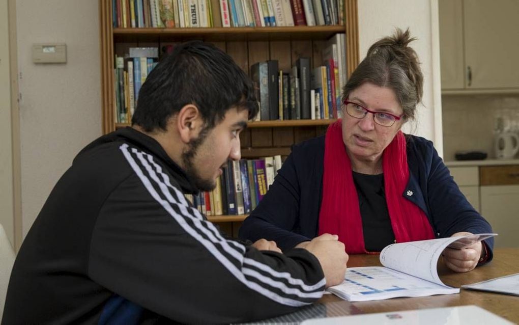 Vrijwilliger Peti van Maldegem geeft Nederlandse les aan een Syrische vluchteling uit de noodopvang in Apeldoorn. beeld RD, Anton Dommerholt