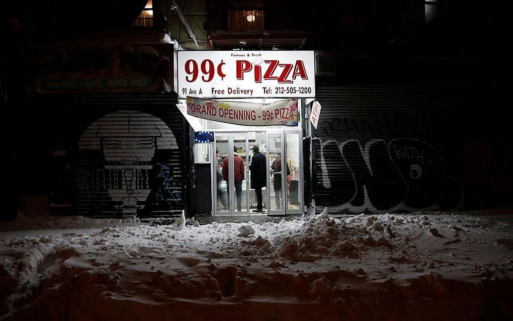 Het openbare leven ligt grotendeels stil door een hevige sneeuwstorm, maar deze pizzeria in New York is gewoon open. Beeld EPA