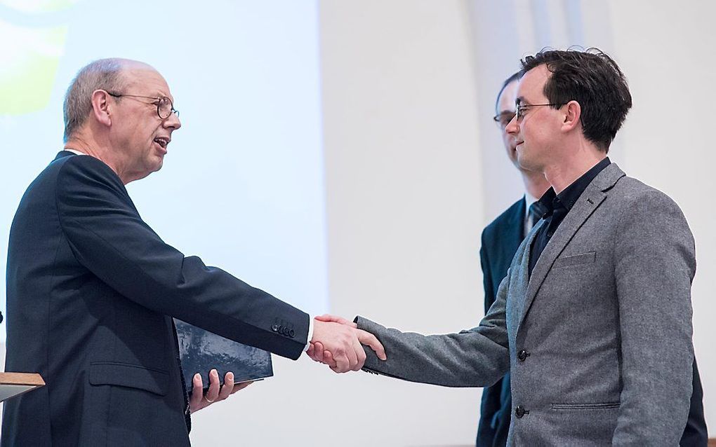 W. B. Kranendonk van uitgeverij De Banier (l.) overhandigt het eerste exemplaar aan hertaler Jasper Stam (op de voorgrond) en prof. dr. W. van Vlastuin. Beeld Niek Stam