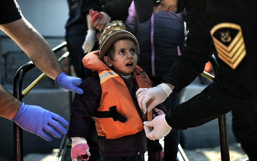 De Griekse ontfermt zich over een jonge migrant op het Griekse eiland Lesbos. beeld AFP