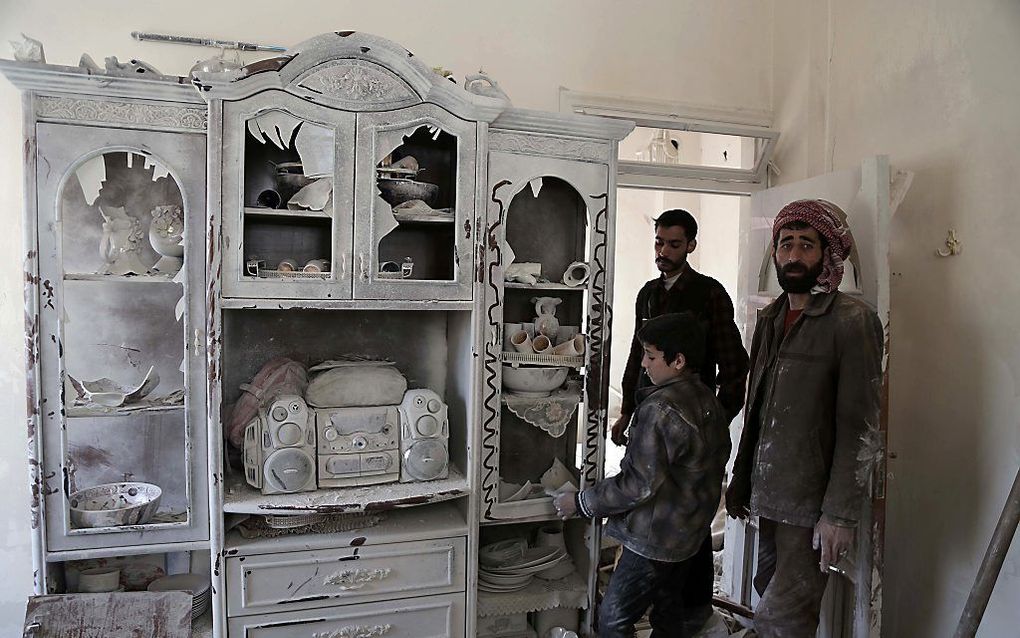 Syriërs in een woning in de stad Douma, die door de bewoners is verlaten. beeld AFP