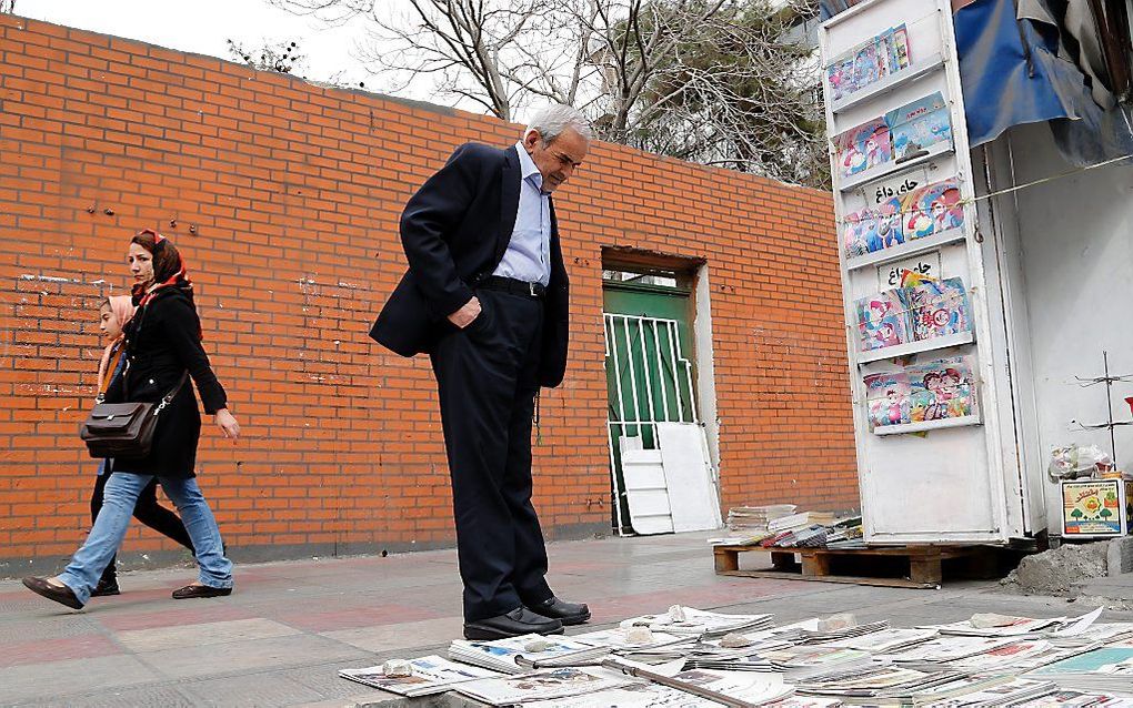 Een Iraanse man bekijkt de kranten bij een kiosk in Teheran. Beeld EPA