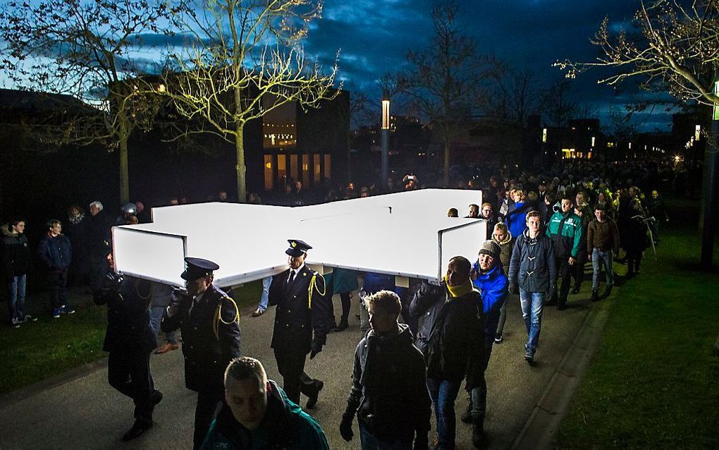 Mensen dragen voor het muziekspektakel The Passion op 2 april 2015 een groot verlicht kruis door de straten van de wijk Roombeek in Enschede.  beeld ANP