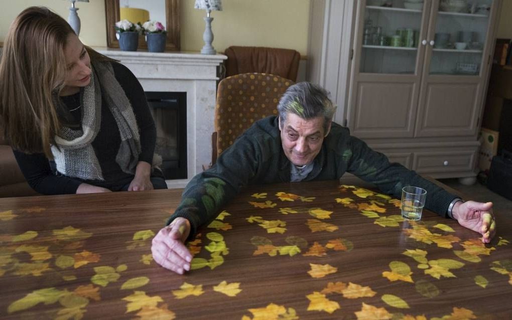 Wie vangt de meeste herfstbladeren? Een bewoner van het Rotterdamse verpleeghuis Pniël, Alcaide, doet een poging. „De spellen van de Tovertafel dagen mensen uit om te bewegen”, merkt activiteitenbegeleidster Jessica Westhoeve (li.).  beeld Dirk Hol