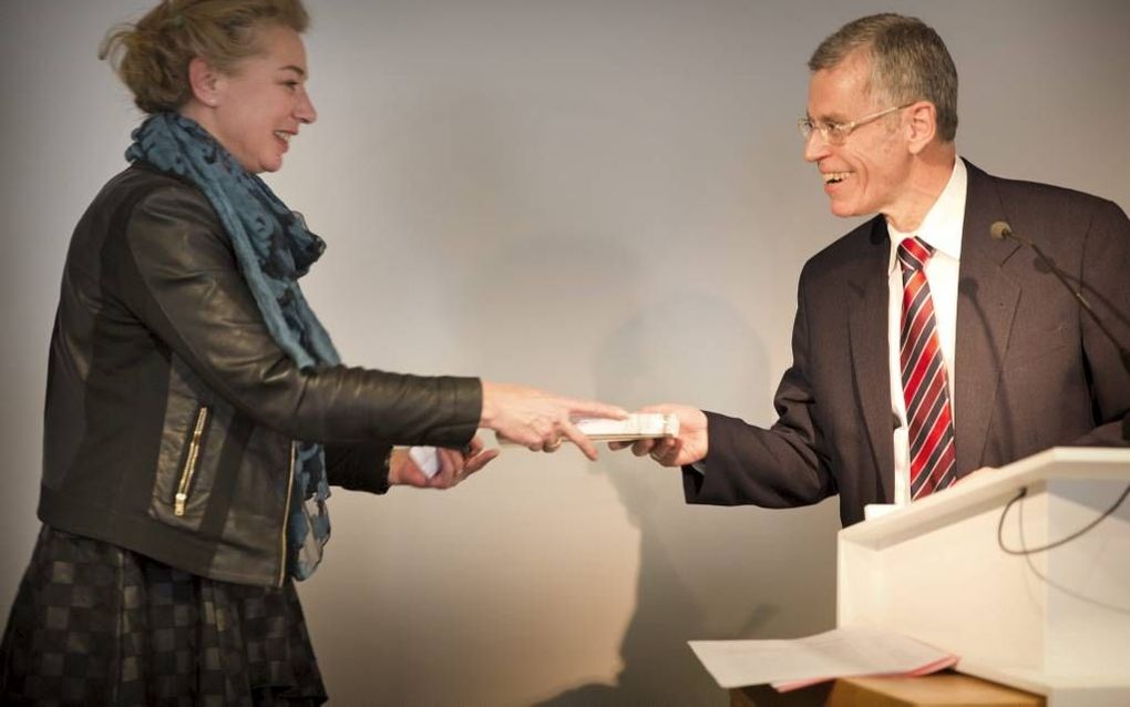 De Amsterdamse dogmaticus prof. dr. Jan Muis (r.) overhandigt een eerste exemplaar van zijn boek aan prof. dr. Mechteld Jansen, rector van de Protestantse Theologische Universiteit. beeld RD, Henk Visscher