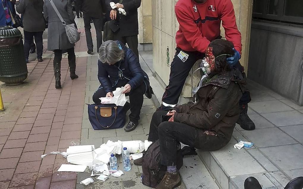 BRUSSEL. Een man helpt een gewonde vrouw kort na de terreuraanslag in het Brusselse metrostation Maalbeek.  beeld AFP, Michael Villa