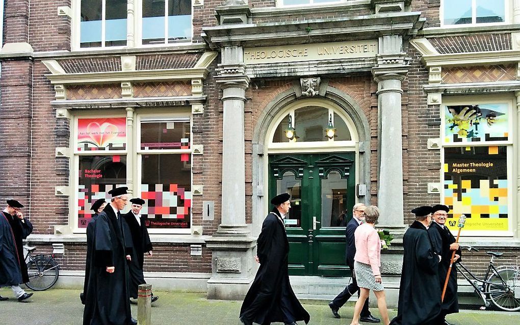 Hoogleraren lopen langs de ingang van de Theologische Universiteit in Kampen. beeld RD