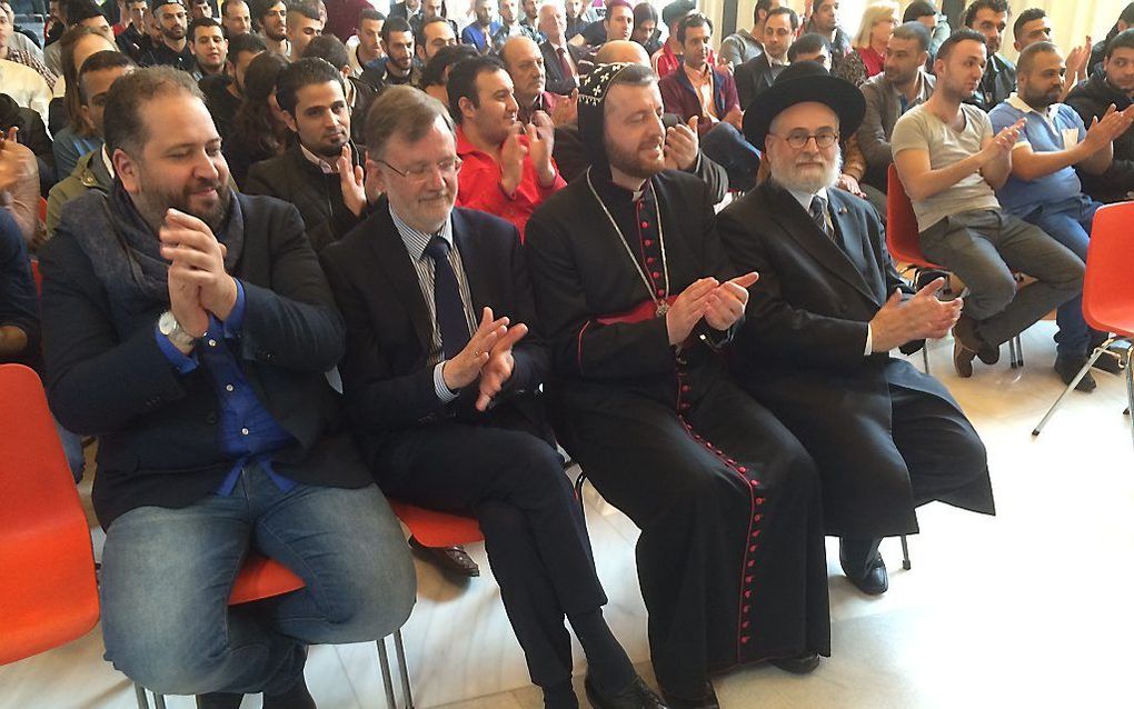 Imam Mohammed Cheppih, ds. A. Plaisier, aartsbisschop Polycarpus en opperrabbijn Binyomin Jacobs (v.l.n.r.) applaudisseren voor de Syrische muzikant tijdens een ontmoeting met vluchtelingen in het stadhuis van Arnhem. beeld RD