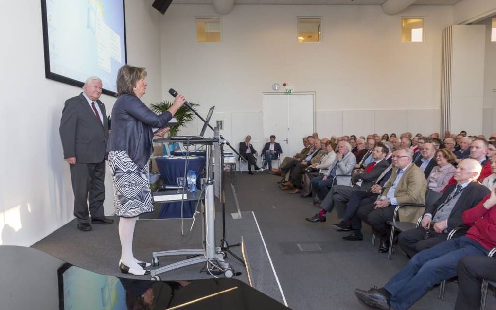 „Ik ben ontroerd om te zien hoe na 43 jaar het gedachtegoed van mijn vader nog steeds actueel is”, zei mevrouw G. Lanting-Boer (achter de katheder). Achter haar dr. ir. J. van der Graaf die het verzameld werk van ds. G. Boer redigeerde en annoteerde. beel