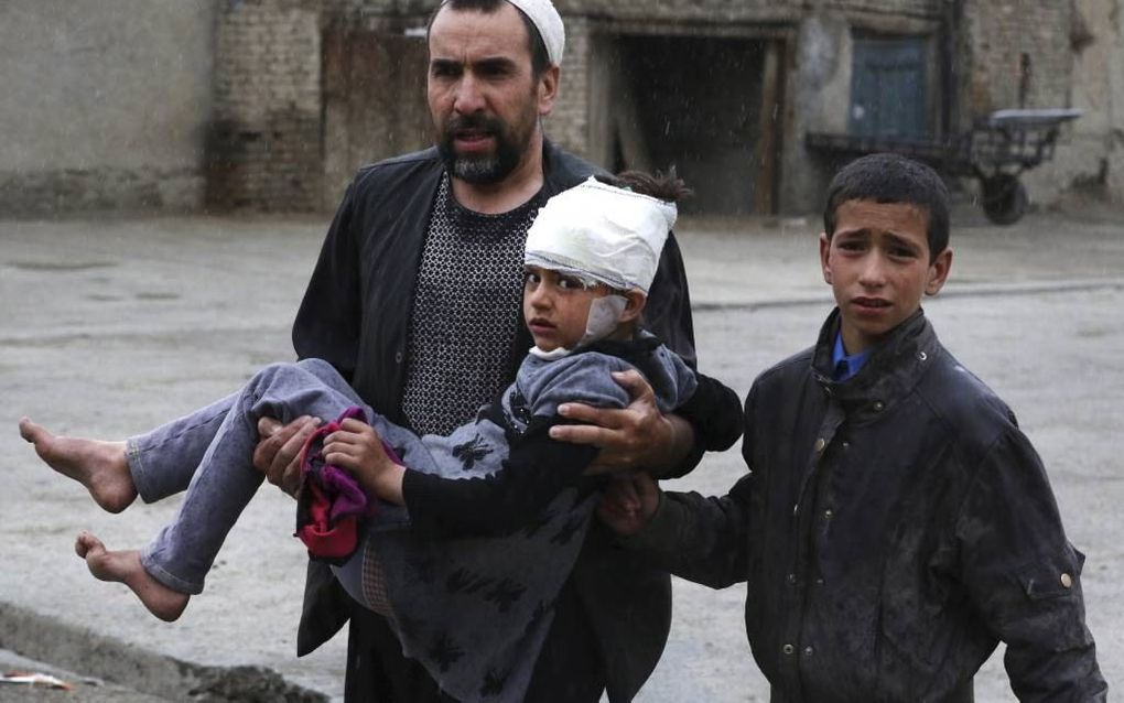 KABUL. Een Afghaanse man draagt een meisje weg dat gisteren gewond raakte bij een zelfmoordaanslag in de Afghaanse hoofdstad Kabul. beeld EPA, Hedayatullah Amid