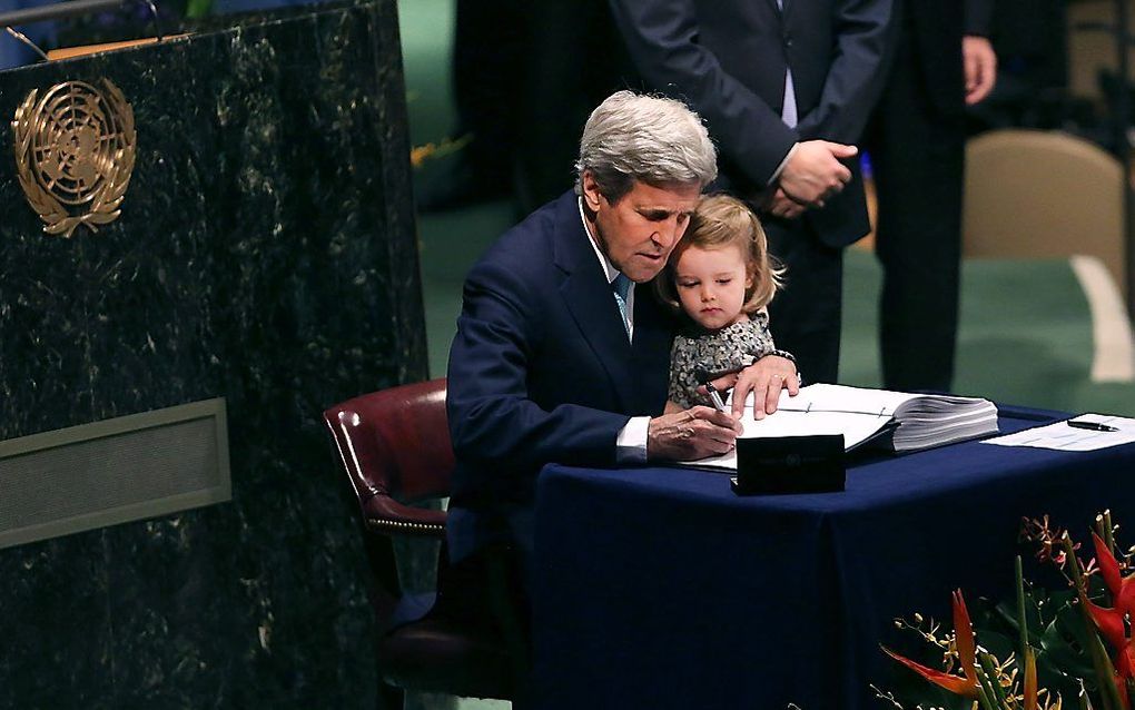 Met zijn kleindochter op schoot ondertekent de Amerikaanse minister van Buitenlandse Zaken John Kerry het klimaatverdrag. beeld AFP