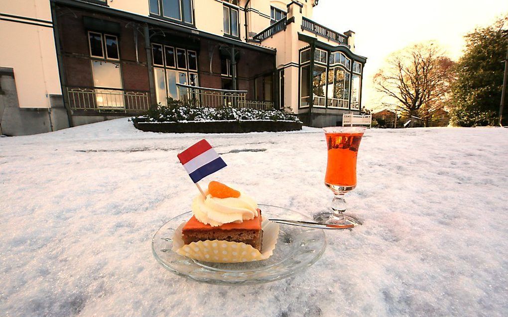 Oranjebitter en oranjegebak staan in de sneeuw in Steenwijk. Beeld ANP