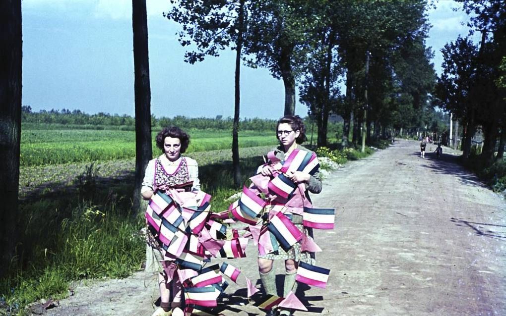 Nelly van Leeuwen en Annie Fenten uit Puiflijk in het Land van Maas en Waal, met een lang koord vol vlaggetjes waarmee ze de Bevrijding vieren. beeld Beeldbank WO2, A. Hustinx