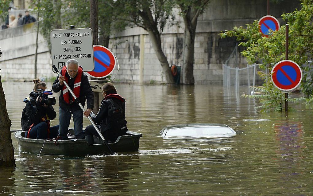 Journalisten in een bootje in de straten van een wijk van Parijs. Beeld AFP