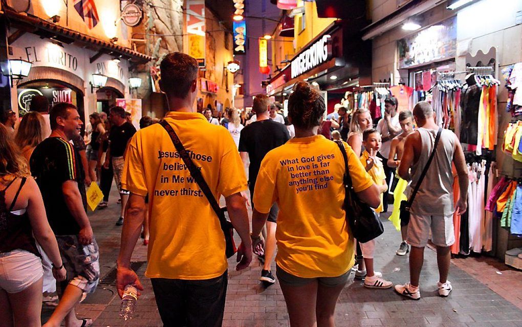 Vrijwilligers verrichten evangelisatiewerk in de Spaanse badplaats Lloret de Mar. De medewerkers van Beach Mission zijn herkenbaar aan hun felgele T-shirts, met achterop een Bijbeltekst.  beeld Beach Mission