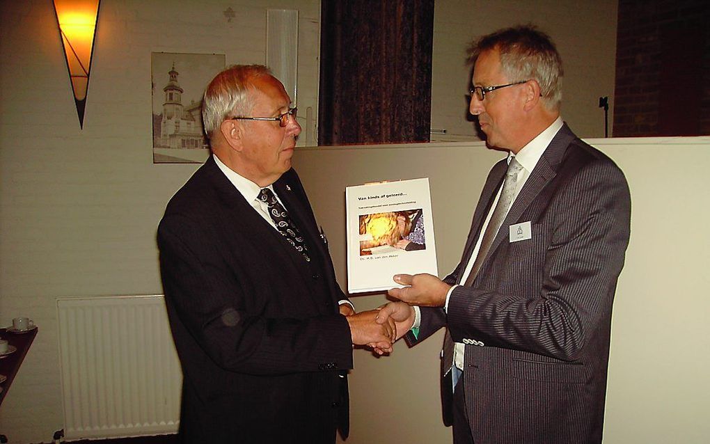 Bestuurslid Cees Codée (rechts) overhandigt het boek aan ds. M. B. van den Akker. Foto RD