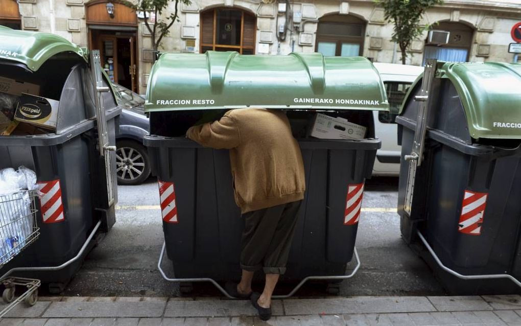 Een man zoekt eten in een vuilniscontainer in het Spaanse Bilbao. De oogst: een sinaasappel en een paar druiven. Volgens liefdadigheidsinstelling Caritas leven meer dan 11 miljoen mensen in Spanje onder de armoedegrens. Het land gaat gebukt onder de finan