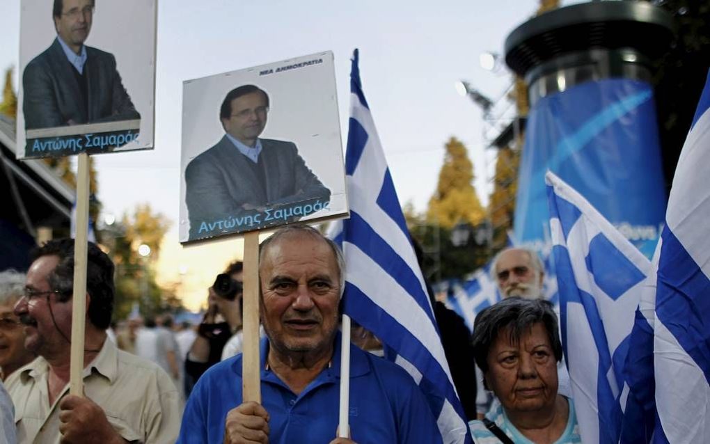 ATHENE – Aanhangers van Antonis Samaras droegen dit weekeinde portretten van de Griekse politicus mee in een bijeenkomst in Athene. De partij Nieuwe Democratie van Samaras won zondag de Griekse parlementsverkiezingen. Foto EPA