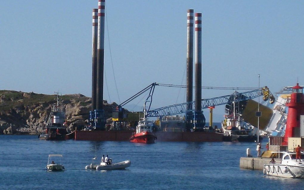 De Costa Concordia wordt vastgemaakt aan een platform. Daarna moeten kranen het 290 meter lange gevaarte rechttrekken. Foto EPA