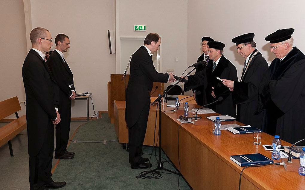 Ds. A. Versluis, geflankeerd door twee broers als paranimf, ontvangt zijn doctorsbul. Rechts (v.l.n.r.): prof. dr. W. van 't Spijker, prof. dr. H. G. L. Peels, prof. dr. T. M. Hofman en prof. dr. C. Houtman. Foto André Dorst