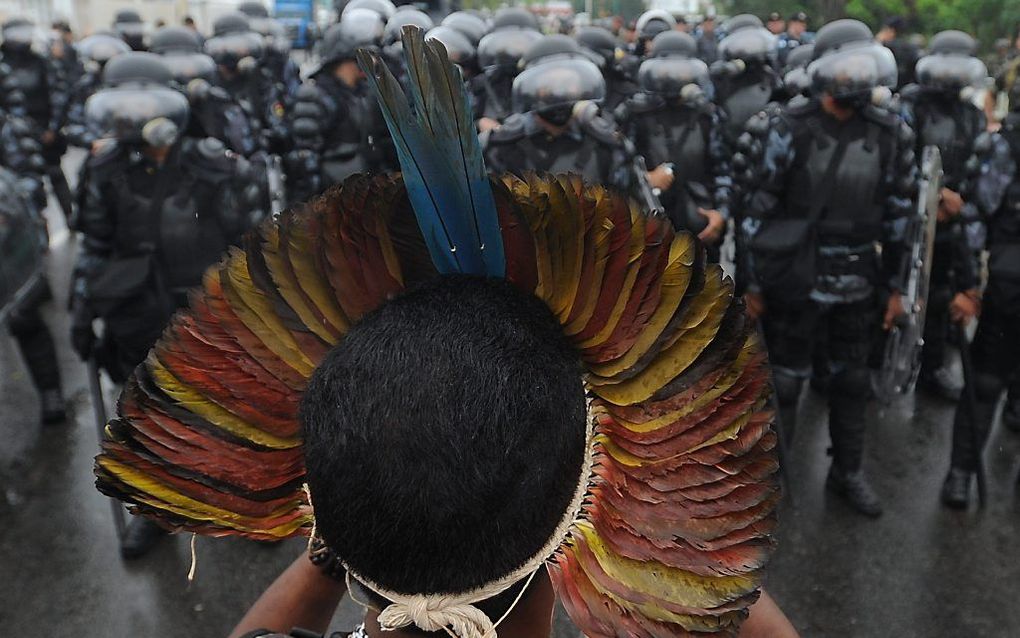 Een demonstrant staat woensdag tegenover een horde politiemensen tijdens de klimaattop in Rio de Janeiro, Brazilië. Foto EPA