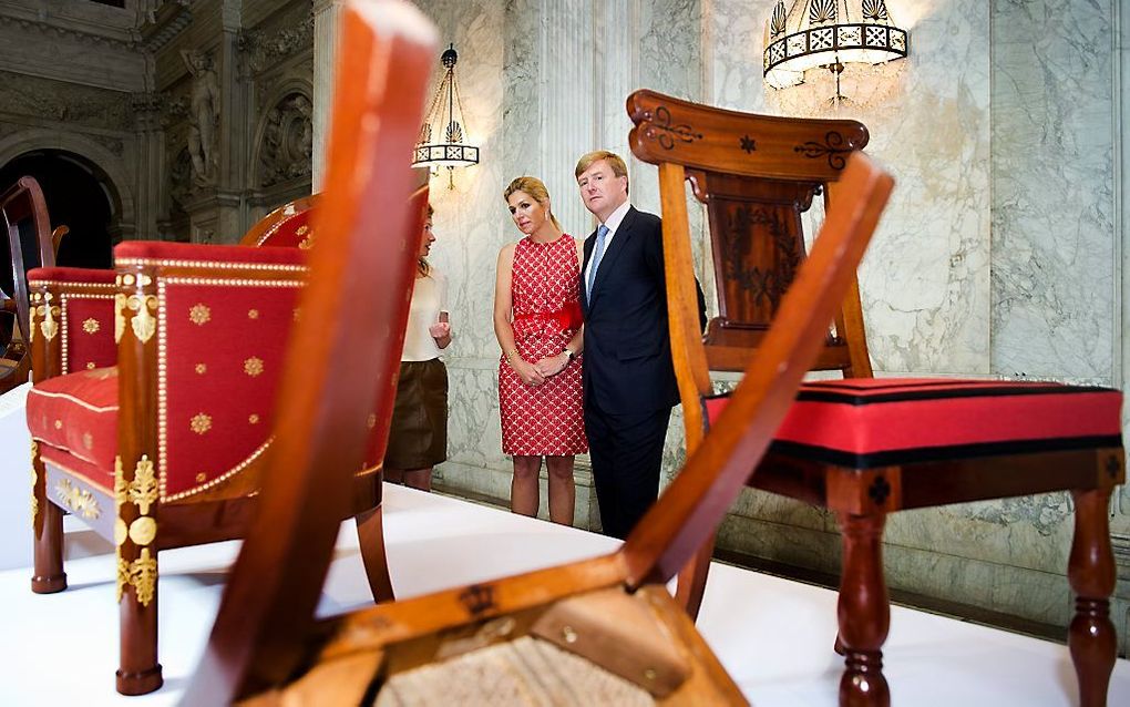 Prins Willem-Alexander en prinses Maxima bekijken in het Koninklijk Paleis de originele stoelen uit de grote eetzaal uit de tijd van Lodewijk. Foto ANP