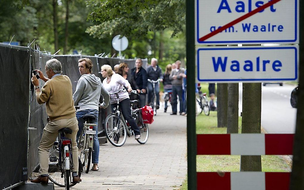 Ramptoeristen kijken door openingen in de zwarte schermen naar het  gemeentehuis in Waalre. Foto ANP