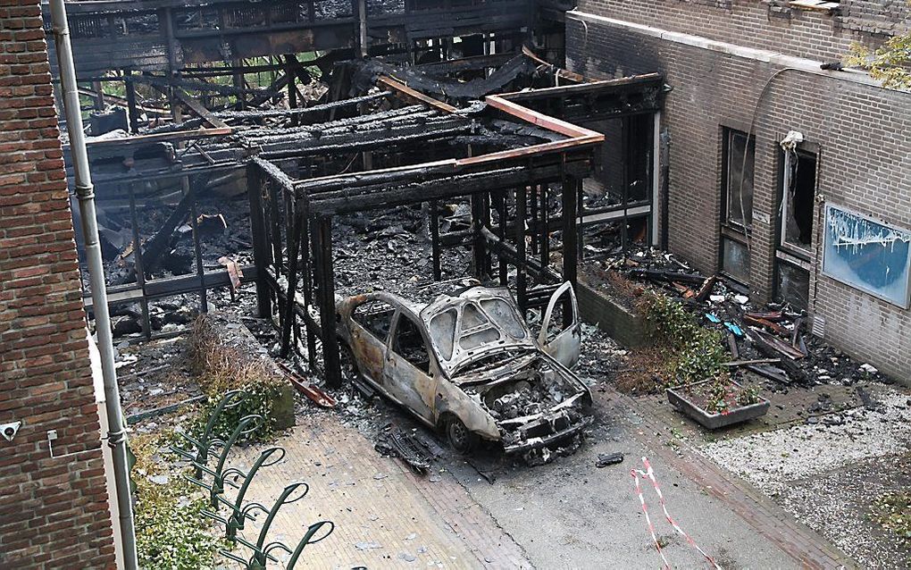 Een uitgebrande auto bij het verwoeste gemeentehuis van Waalre. Foto ANP