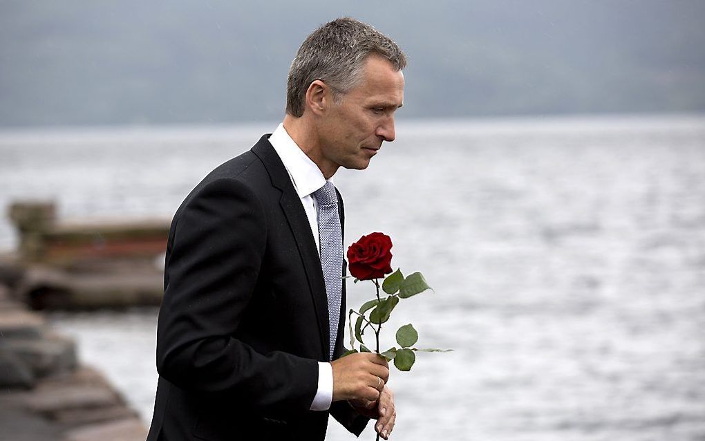 De Noorse premier Jens Stoltenberg loopt met roos richting de herdenkingsbijeenkomst op het eiland Utoya, waar een kranslegging zal plaatsvinden. Foto ANP