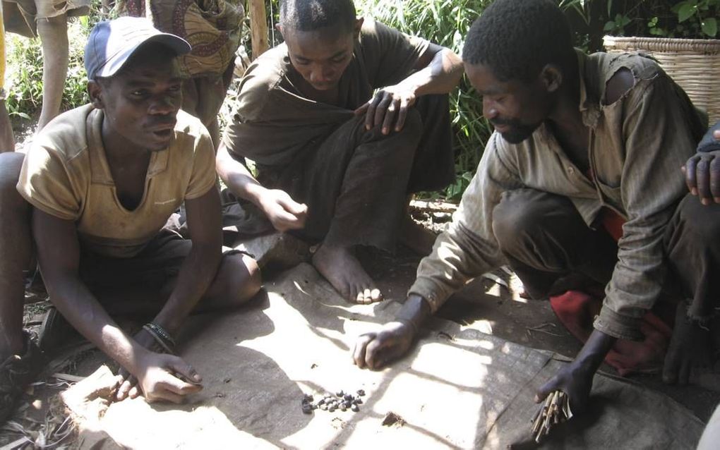 Pygmeeën in de bergen van de Congolese Zuid-Kivu maken zich op voor eens spelletje. Een handvol steentjes is genoeg om het te spelen. Overal in Afrika wordt er driftig (varianten van) mancala of bao gespeeld. Foto RD