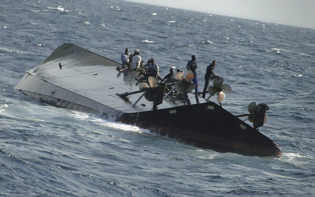 Overlevenden wachten op hulp om de gekapseisde veerboot. Foto EPA