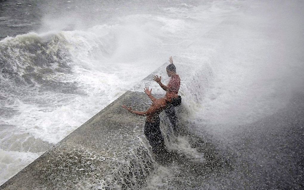 Twee Filipijnse mannen trotseren de golven langs de kust van Manila. Foto EPA