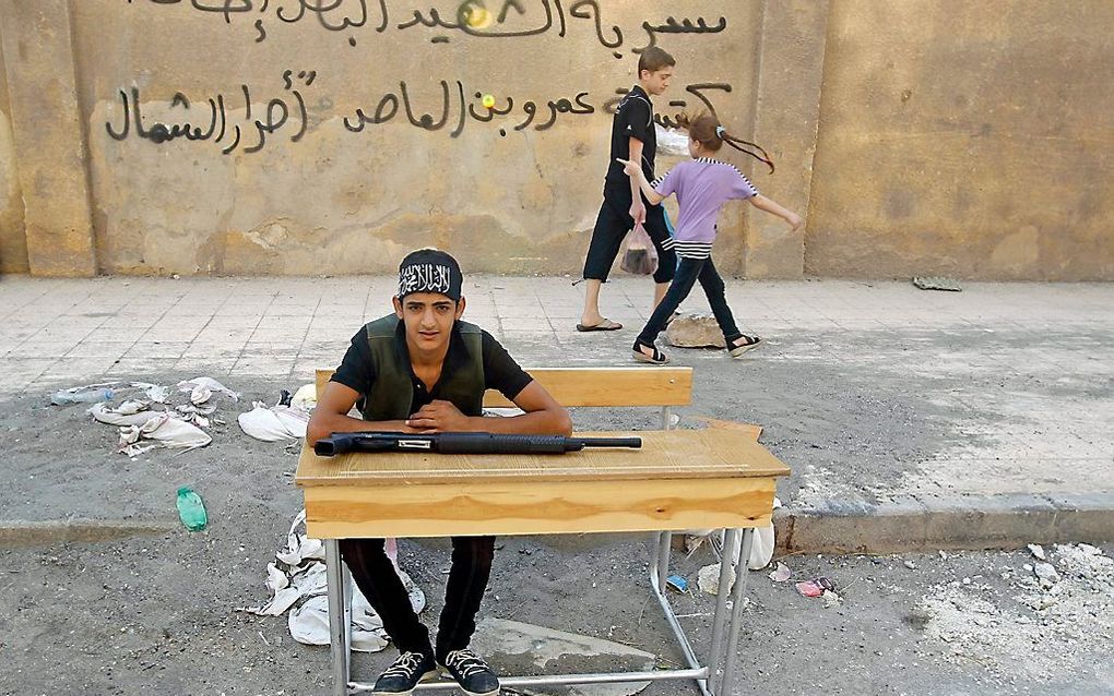 Een Syrische strijder rust uit op een schoolbankje in Aleppo. Foto EPA