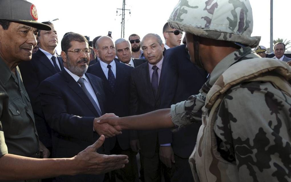 De Egyptische president Morsi (2e van l.) bezocht maandag samen met minister van Defensie Tantawi (l.) de grens langs de Gazastrook. Bij een aanslag zondag kwamen zestien mensen om. Foto EPA