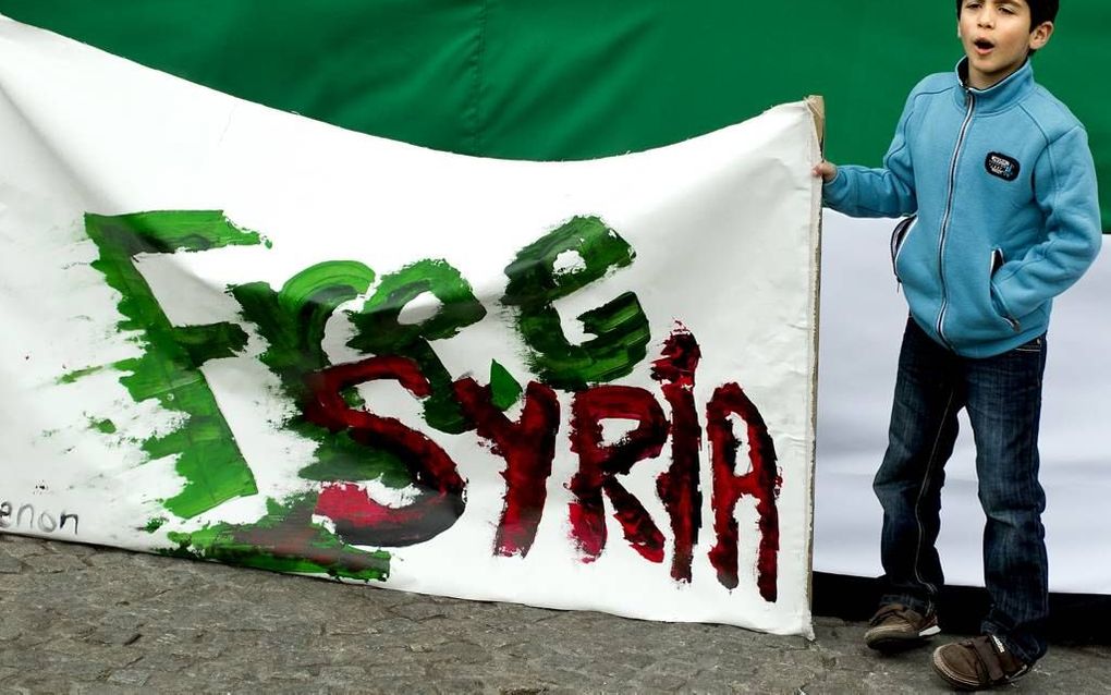 Een jonge demonstrant vraagt op de Dam in Amsterdam aandacht voor de strijd tegen het regime in Syrië tijdens een demonstratie van Syriërs in Nederland. Foto ANP