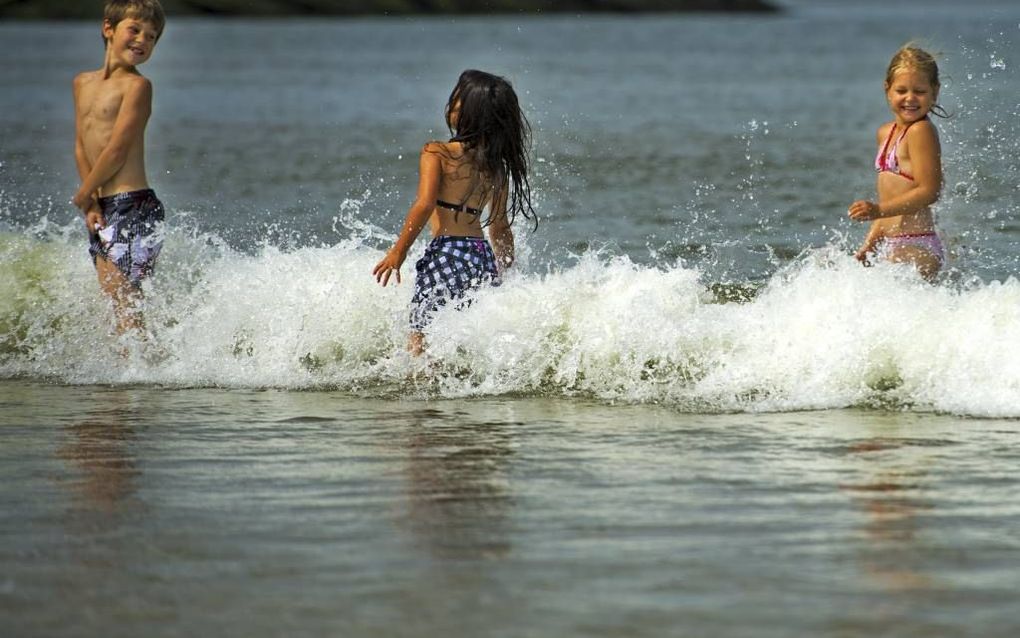 Kinderen speelden gisteren in de zee bij het havenhoofd van Scheveningen. Foto ANP