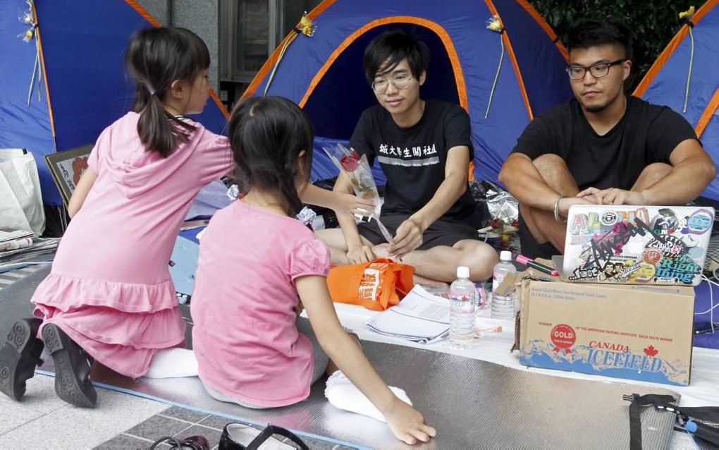 Twee meisjes boden vorige week in Hongkong enkele studenten een roos aan, nadat die in hongerstaking waren gegaan uit protest tegen de invoering van een omstreden schoolvak.  Foto EPA