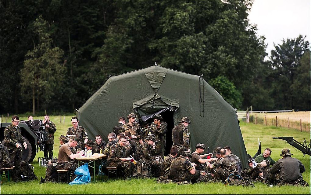 Militairen rusten uit tijdens de derde dag van de Nijmeegse Vierdaagse.  Foto ANP