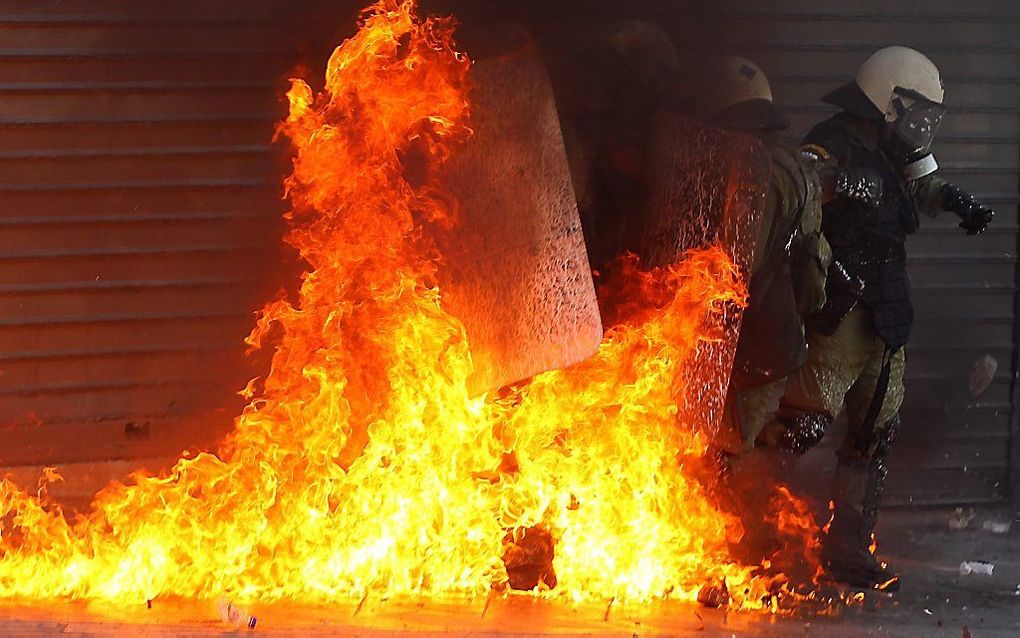 Een politieman wordt getroffen door een molotovcocktail tijdens demonstraties in Athene. Foto EPA