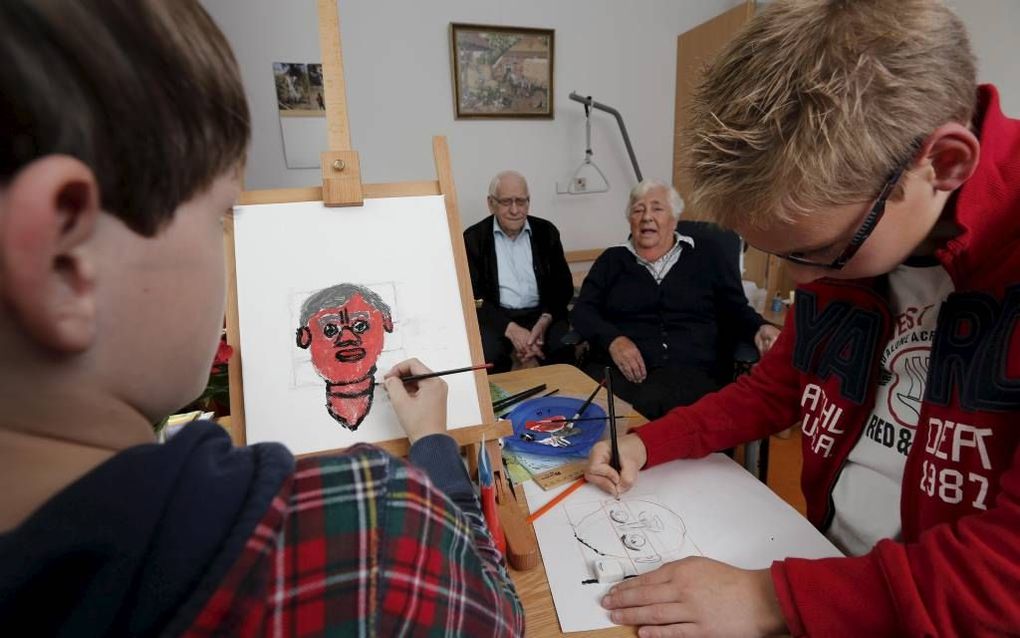 Corné (li.) en Lucas portretteren mevrouw Verburg, bewoonster van zorgcentrum Wilgenhoven in Stolwijk. Foto Fotoburo Martin Droog.