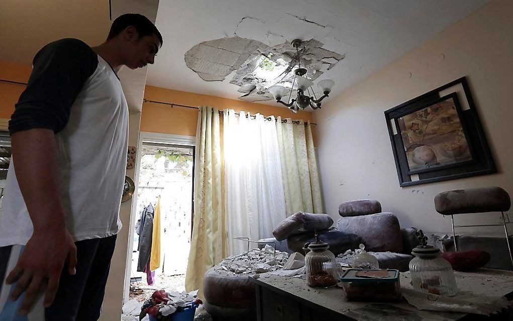 Een Israëlische man bekijkt de verwoesting die een raket vanuit de Gazastrook heeft aangericht aan zijn huis. Foto EPA