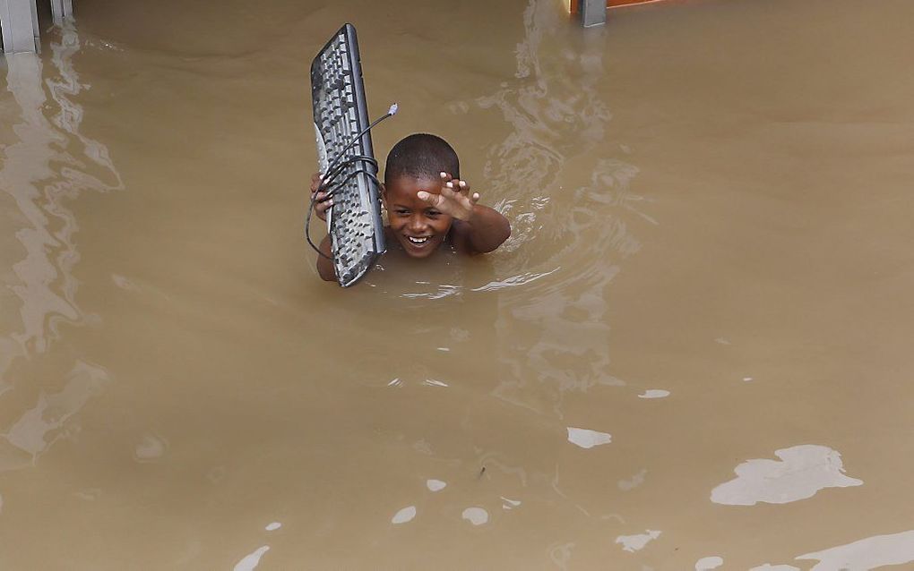 Een kind haalt een keyboard uit het water in La Barquita.  Foto EPA