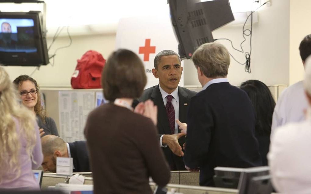 Barack Obama (m.) begroette dinsdag medewerkers op het hoofdkantoor van het Rode Kruis in Washington. De president heeft besloten zijn verkiezingscampagne te staken en zich geheel te wijden aan zijn taak als rampenbestrijder.  Foto EPA