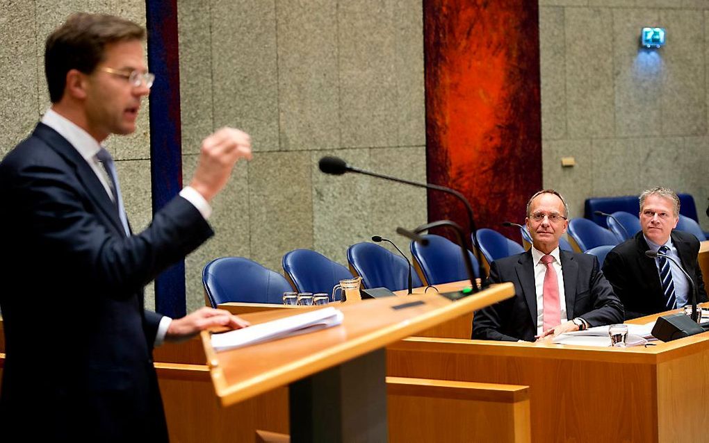 VVD-leider Mark Rutte spreekt in de Tweede Kamer tijdens het debat over de kabinetsformatie en het regeerakkoord, informateurs Henk Kamp en Wouter Bos kijken toe. Foto ANP