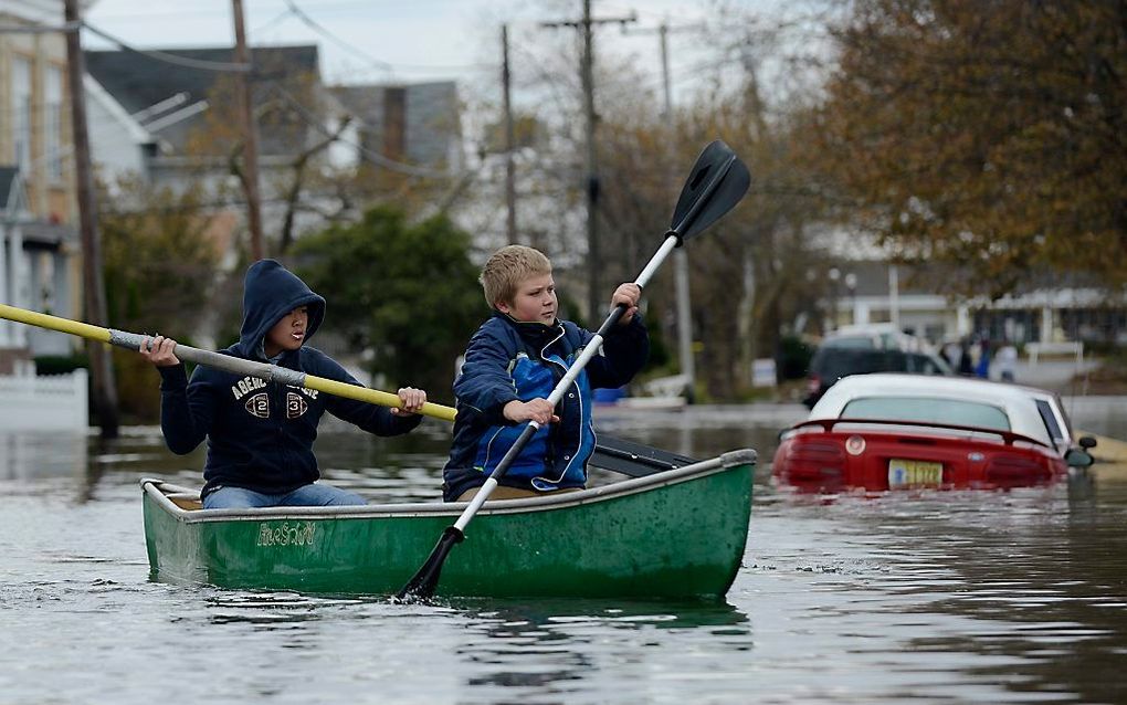 Jongens in een ondergelopen straat in New Jersey. Foto EPA