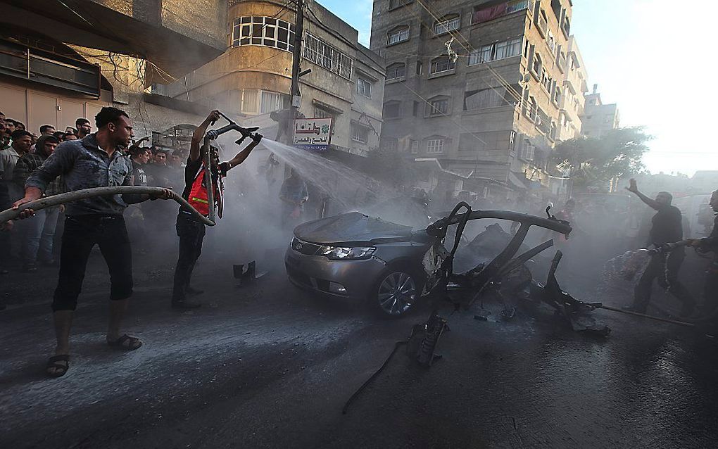 Brandweerlieden blussen de zwaarbeschadigde auto van Hamasleider Ahmed Jabari, nadat deze woensdag werd geraakt door een Israëlische raket Gaza-Stad. Foto EPA